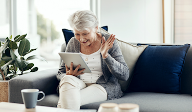 illustratie oudere vrouw met tablet thuis op de bank